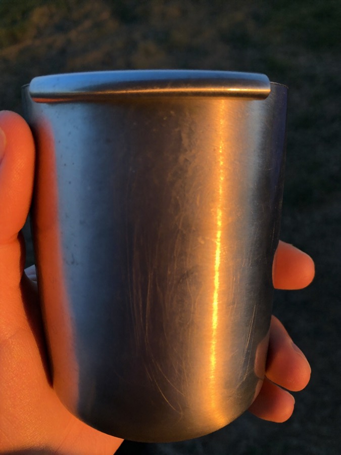 Illustration: a plain steel cup held in a hand in the blue light an hour before sunrise.